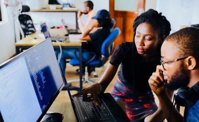 An image of people working on a laptop and a computer